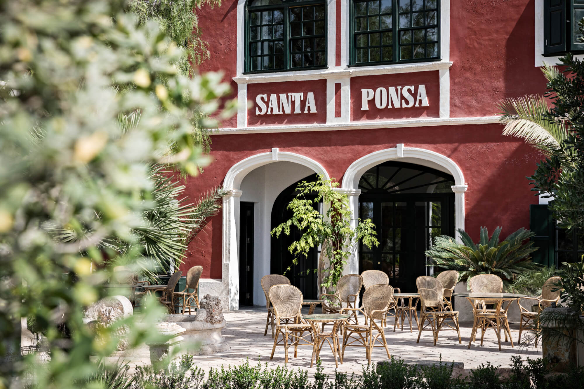 The main house of the Santa Ponsa estate seen through terraced gardens with palms, citrus trees and pomegranate trees in the foreground